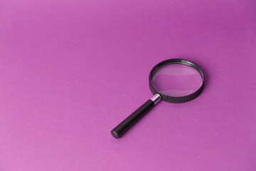 Magnifying glass isolated on a lilac background. Side view from above. A place to copy.