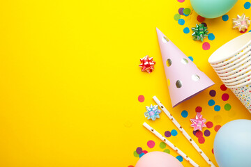 Colorful carnival or party frame of balloons, streamers and confetti on yellow background. Space for text