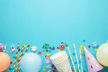 Colorful carnival or party frame of balloons, streamers and confetti on blue background. Space for...