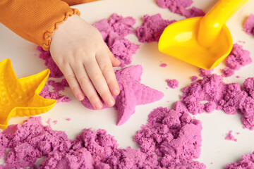 Obraz na płótnie Canvas Kids creativity. Kinetic sand games for child development at home. Sand therapy. Children's hands making starfish.