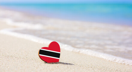 Trinidad and Tobago flag in the shape of a heart on a sandy beach. The concept of the best holiday...