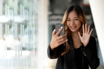 Young asian businesswoman beautiful charming smiling having a video call with a smart phone at office