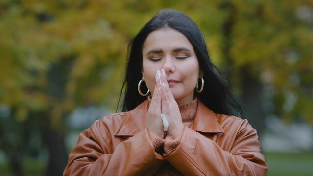 Young ill hispanic woman standing outdoors sneezing into handkerchief wiping nose feeling unwell illness seasonal cold allergy suffering from coryza disease symptoms respiratory virus rhinitis flu
