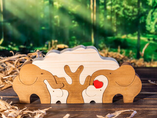 Wooden puzzle in the form of a family of handmade elephants on the background of the forest