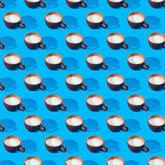 Pattern from a brown mug with a shadow with fresh milk on a blue background. Seamless pattern