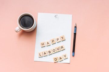 Words happy labor day are laid out on paper next to cup and pen.