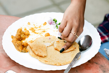 Indian food Chole bhature on white plate , eating with hand, close up, top view, partial focus