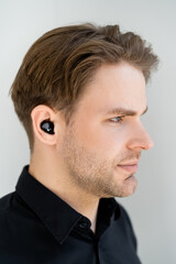 Obraz premium profile of young man listening music in wireless earphone isolated on grey.