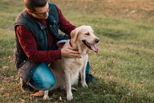 Golden retriever dog sitting with owner outdoors