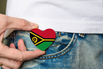 Wooden badge with Vanuatu flag in the shape of a heart in a man's hand