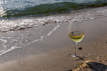 Romantic glass of white wine, on the sea beach. Wine tasting and relaxation at the resort