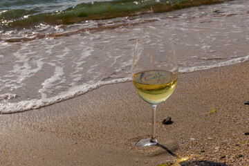 Romantic glass of white wine, on the sea beach. Wine tasting and relaxation at the resort