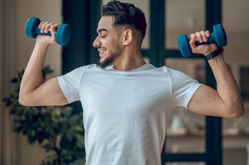 Fototapeta na wymiar Handsome young man having a workout with dumbbells