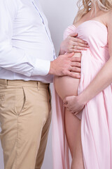 Pregnant woman and her husband close-up hands on a white background in the studio