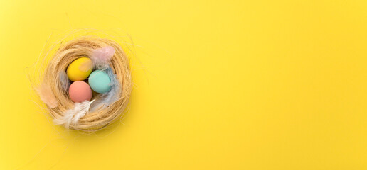 Happy Easter card. colored pink easter eggs on a yellow nest background from above, image with selective focus. Place for text. Wide banner