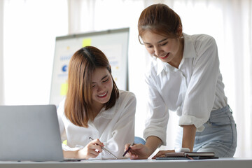 Two female colleagues consulting and working together in the office.