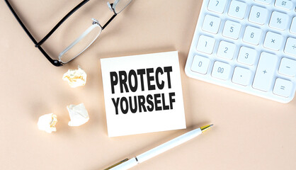 PROTECT YOURSELF text on sticky with pen ,calculator and glasses on a beige background