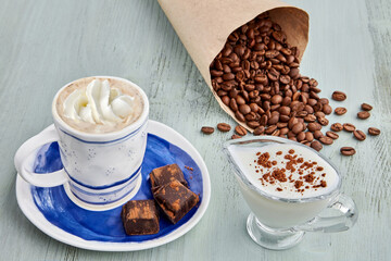 Cup of coffee with whipped cream and milk, chopped chocolate