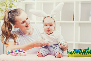 Obraz na płótnie Canvas Happy Mother and baby with bunny ears playing Easter egg.