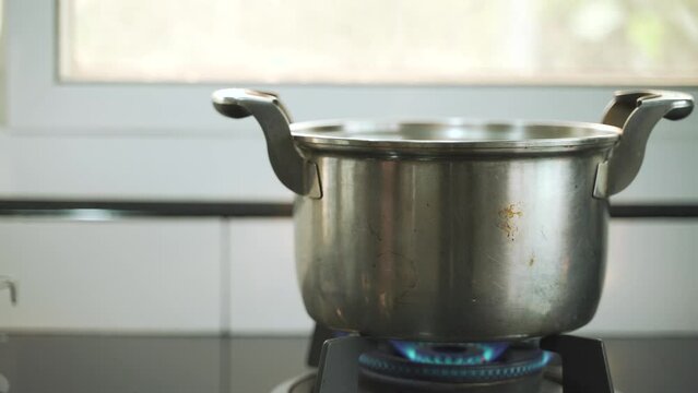 Boiling hot water soup in stainless steel pot over gas stove