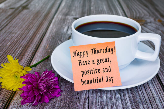 Motivational quote written on sticky note with white coffee cup and flowers.