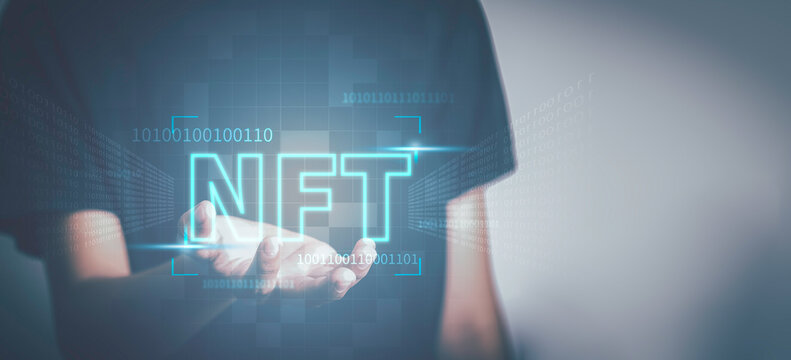 NFT non fungible tokens concept. Businessman holding digital unique art NFT text hologram on blue light
