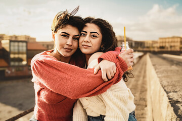 Couple of young teen girlfriends hugging outdoors by the harbor, hugging and looking at the camera...