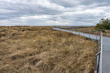 Półwysep Helski w Polsce, ścieżka po wydmach plaża na cyplu na Helu, trawa rosnąca na wydmach.