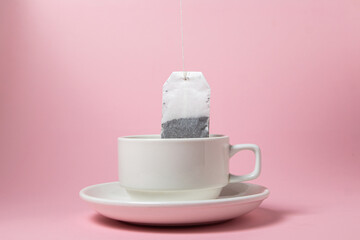Tea bag in a white cup on a pink background. A quick and easy way to brew tea.