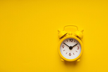 Yellow alarm clock on a yellow background.