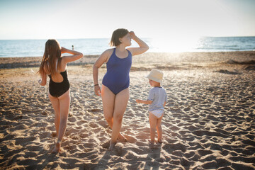 Three children of girls in swimsuits run on the sand and play on the beach. Summer holidays and adventures of siblings. Active games on the sea coast. overweight child