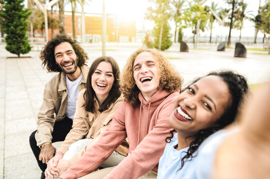Multiracial group of smiling friends make selfie photo with smartphone camera while traveling on vacation - Funny people taking picture in a urban street - Outdoor activity of young students concept.