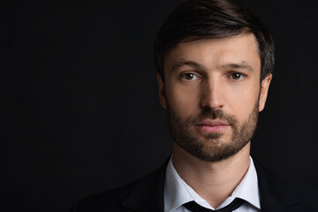 Portrait Of Confident Businessman Looking At Camera Over Black Background