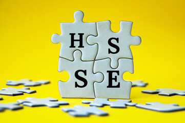 Short form text of HSSE on jigsaw puzzle with yellow background - Health, Safety, Security and...