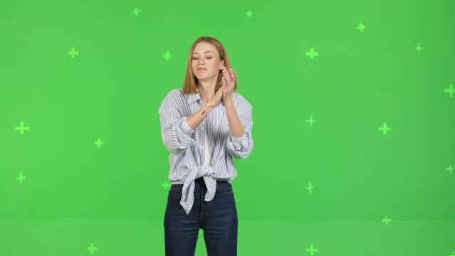 Portrait of excited woman clapping in hands, applauding and looking at camera with smile, bravo, wearing shirt. studio shot isolated on green screen background