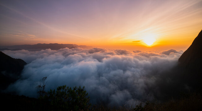 sunset over the mountains with awesome clouds,  Creamy fog covered the mountain dramatic sunrise image taken from Munnar Kolukkumalai Kerala
