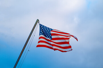 sunlit american flag against a gray sky