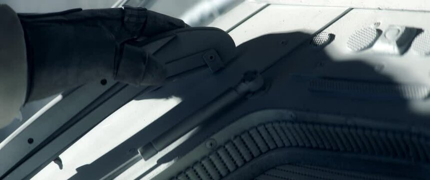 Close up on hand - astronaut performing spacewalk, working on a outer part of a space craft. Space exploration, Mars mission. Shot with 2x anamorphic lens