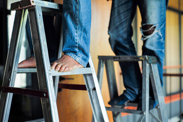 Selective focus on the aluminum ladder with defocused feet of workers working on it © Phichat