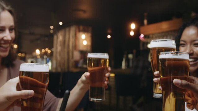 Multi-ethnic group of friends clinking glasses of beer at a restaurant.