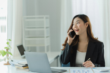 Obraz premium Asian business woman using smart phone and laptop in office.