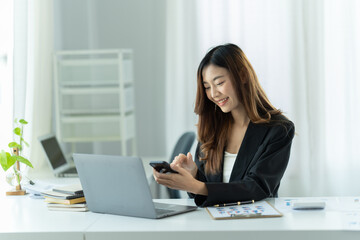 Asian businesswoman relax and enjoy chatting mobile phone at office.