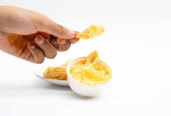 yellow corn chips in a hand with white souce isolated on white background, selective focus
