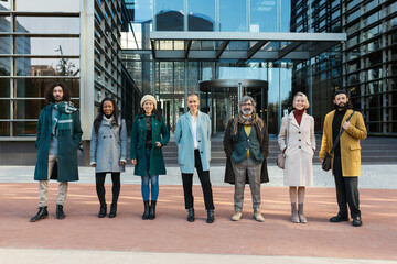 Diverse coworkers standing on street with glass walls