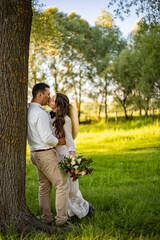 a couple in love in wedding dresses in a meadow stand near a tree. method for text