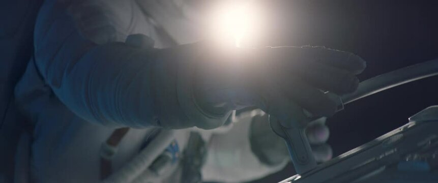 Female astronaut performing spacewalk, working on a outer part of a space craft. Shot with 2x anamorphic lens