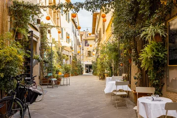 Fototapeten Enge Straßen Beautifully landscaped narrow street with restaurant tables in the old town of Grosseto, in Maremma region of Italy. Cozy city view of the old Italian town  © rh2010