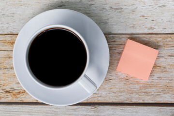 Note with white coffee cup on wooden desk. Flat lay. Copy space.