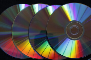 Discos de cd superpuestos para grabaciones de datos y almacenamiento, iluminados con luz lateral forman colores brillantes de arco iris por reflecciòn, presentan un bello diseño gràcfico para fondos