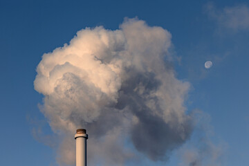 the smog above an industrial chimney on a clear blue sky background. 